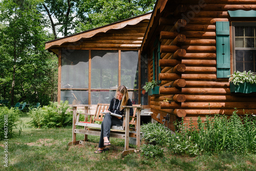 Woman writing by a log cabin photo