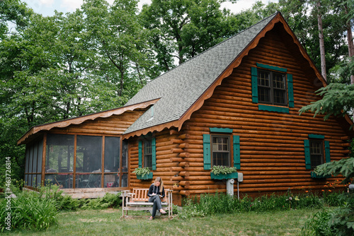 Woman drawing by a log cabin photo