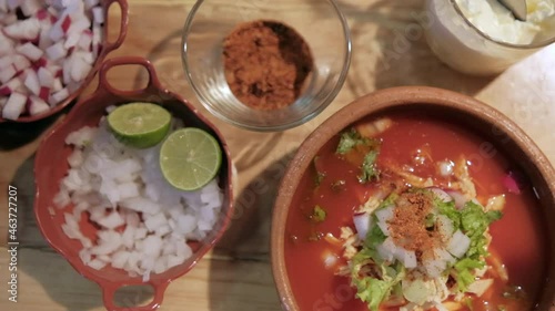 Clay bowls of chopped vegetables and delicious traditional Mexican pozole