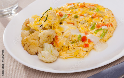 Tasty omelet with vegetables served with baked cauliflower and delicate cheese sauce..