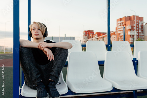 Adolescent in headphones sitting on grandstand photo