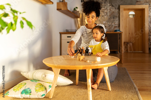 Child and adult playing with toy animals at home photo