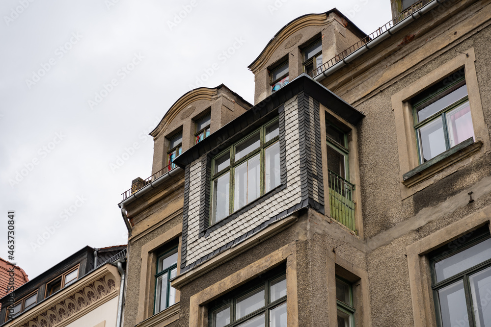 Detail of the facade of an old building. Looking up to the roof. Historic architecture of a residential house in East Germany. Weathered wall outdoor.