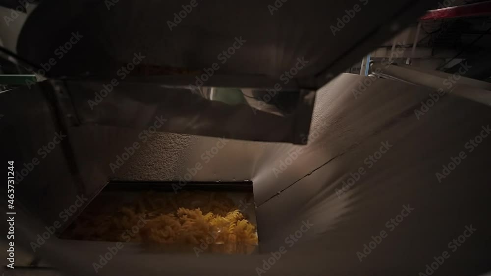 Pasta and Noodles Factory. Dropping Fusilli or Rotini from a one Conveyor Belt to another. Close filmed machine work at food industry Pasta and Noodles Factory. Dropping Fusilli or Rotini from a one Conveyor Belt to another. Close filmed machine work at food industry