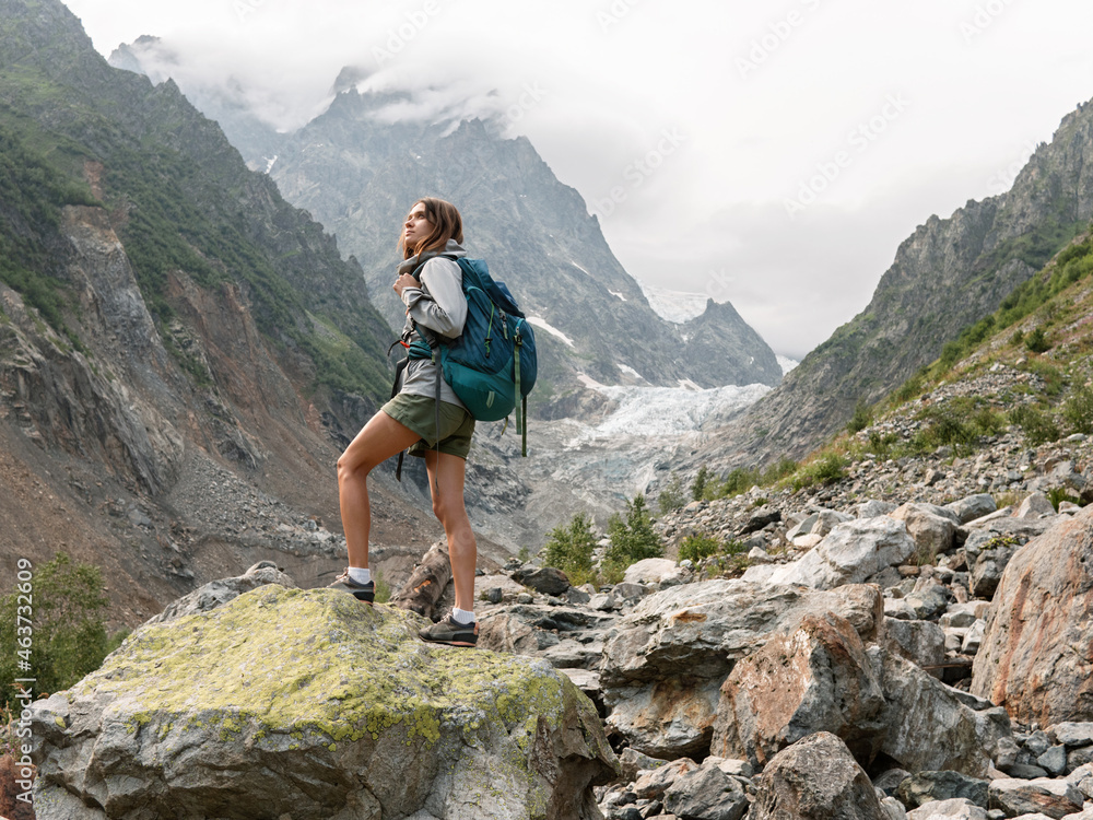 Female traveller standing on the rock in mountain area Female traveller standing on the rock in mountain area