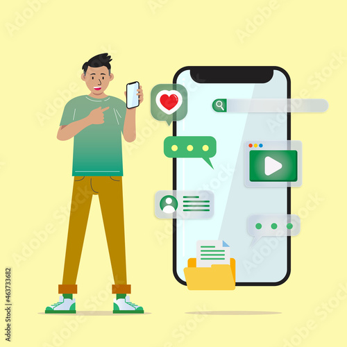 A young businessman is standing in a green shirt, smiling and showing a smartphone screen in his hand. The guy holds a smartphone.