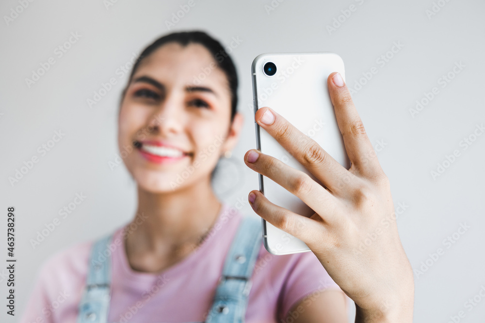 Young latin woman take selfie from hands phone on gray background in Latin America Young latin woman take selfie from hands phone on gray background in Latin America