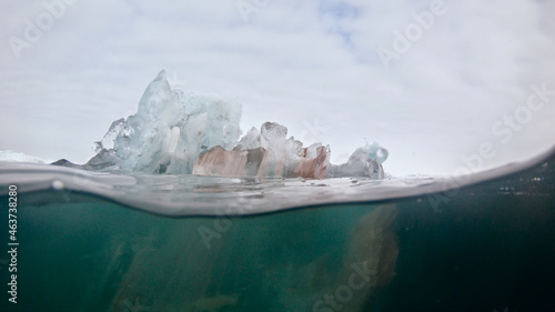 Melting translucent bergy bit of ice on water-line, Arctic Greenland photo