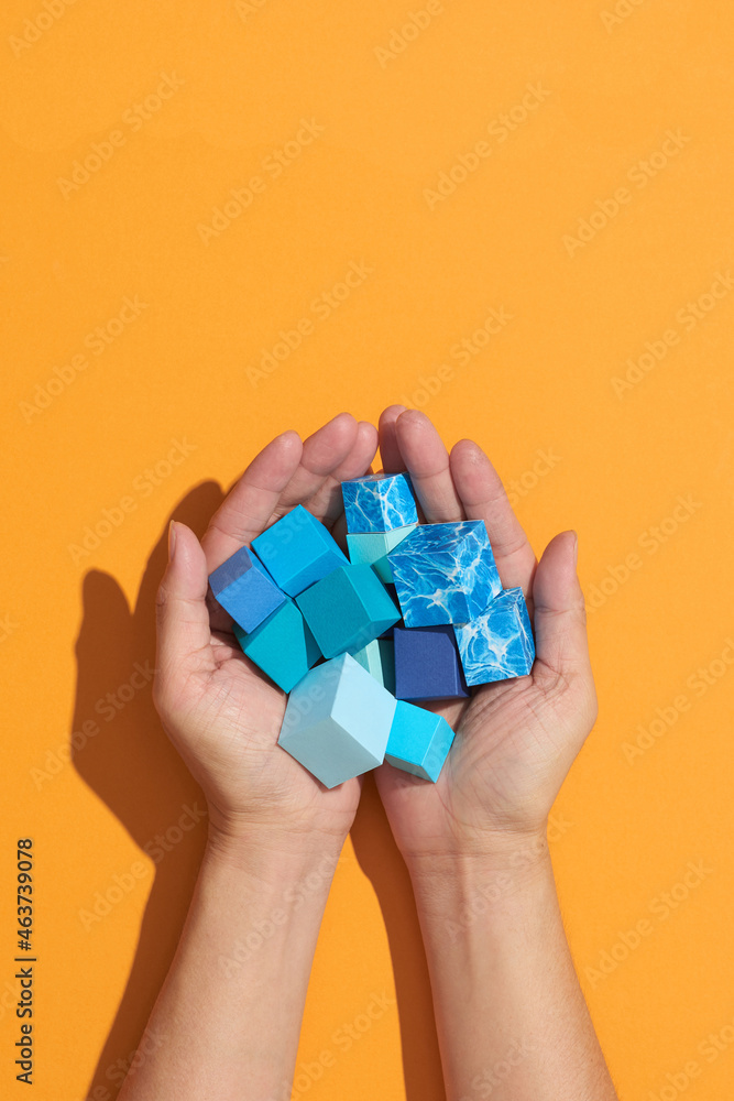 Elevated View Of A Human Hand Holding blue Cubes Elevated View Of A Human Hand Holding blue Cubes