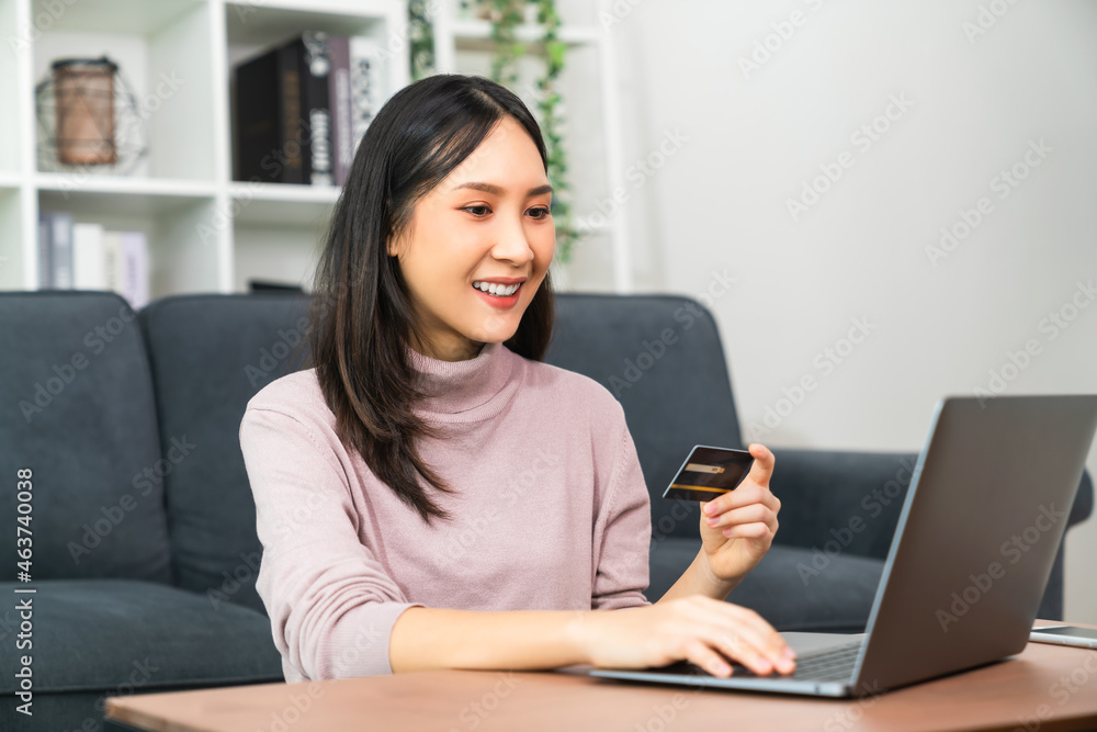 Young Asian woman holding credit card and using laptop for shopping online with payment on internet banking. Young Asian woman holding credit card and using laptop for shopping online with payment on internet banking.