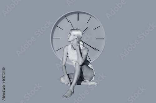 Young woman sitting before a clock photo