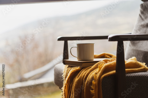 Detail of coffe cup and book on top of chair by window photo
