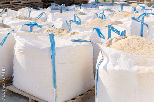 Bags with bulk construction materials standing in rows in outdoor storage. photo