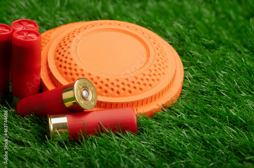 Clay disc flying targets and shotgun bullets on green grass background ,Clay Pigeon target