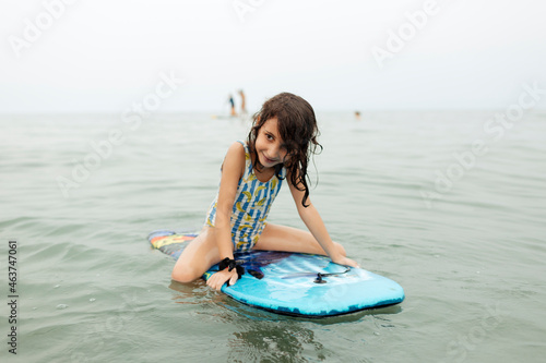 Young girl on bodyboard inside the sea smiling. photo