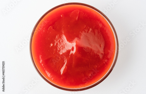 Tomato ketchup in glass bowl on white background.