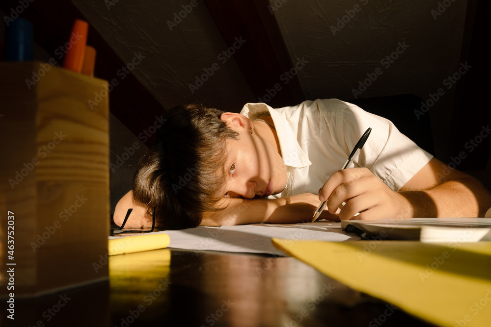 Young bored student lying on the table looking at the camera Young bored student lying on the table looking at the camera