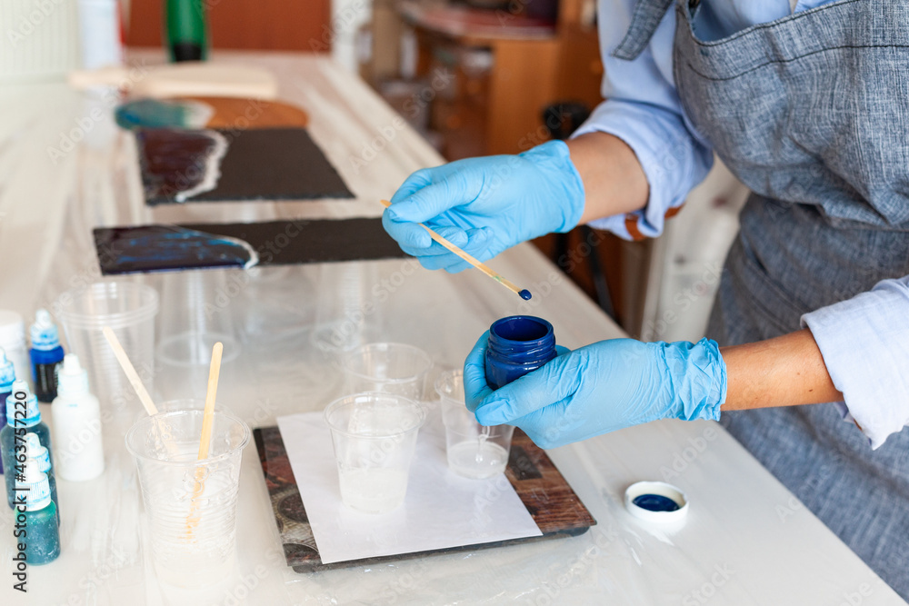 Fototapeta premium Mixing process of two resin components for creativity, close-up, gloved hands, resin art master class