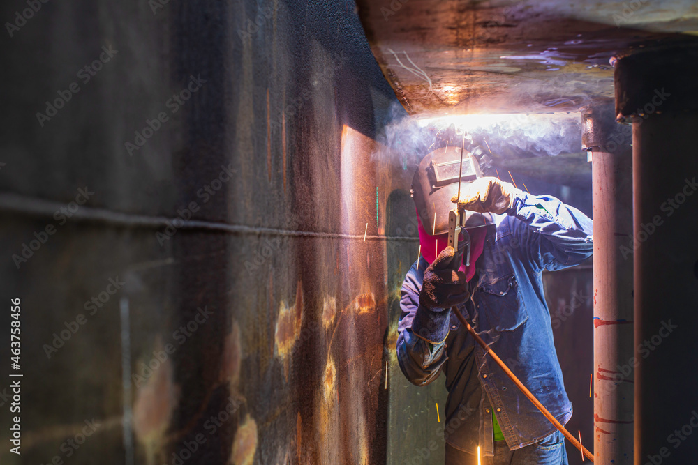Fototapeta premium Welding male worker metal arc is part in machinery tank nozzle pipeline construction tank oil inside confined spaces.