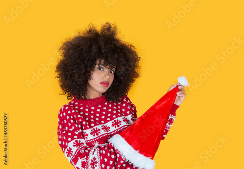 pretty latin hispanic woman, christmas santa claus hat, yellow background