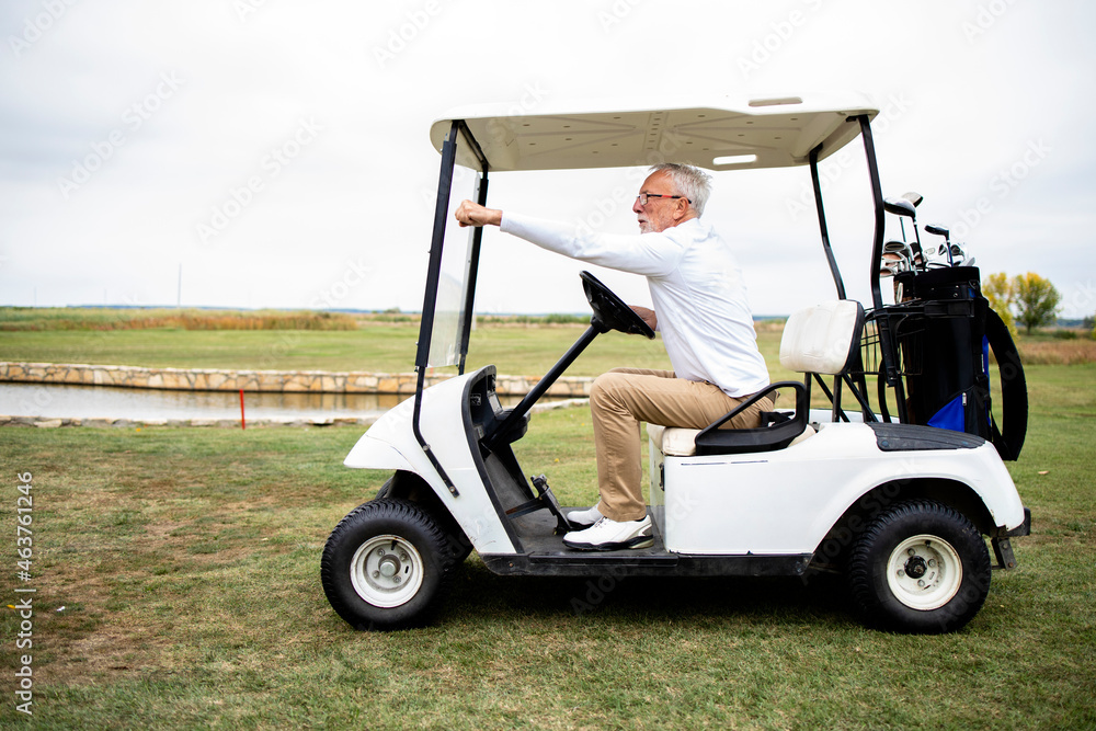 Senior man driving golf car to the green zone to continue playing golf. Senior man driving golf car to the green zone to continue playing golf.