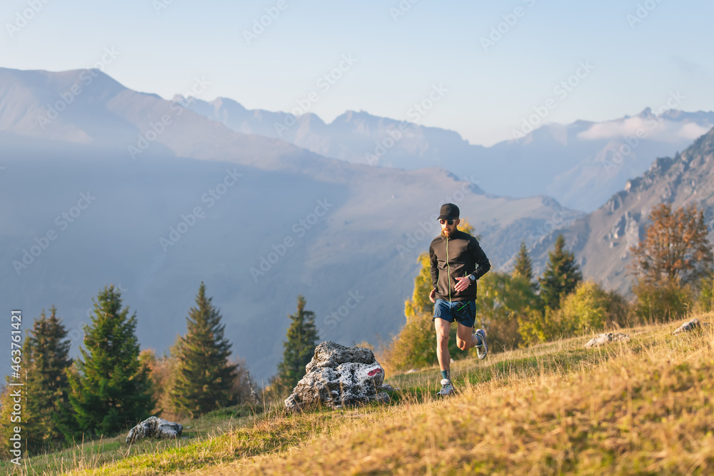 Athlete man runs through mountain meadows in autumn.