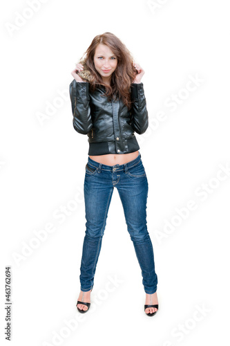 Full length portrait of a slim young woman wearing a leather jacket, blue jeans and high heels, isolated in front of white studio background