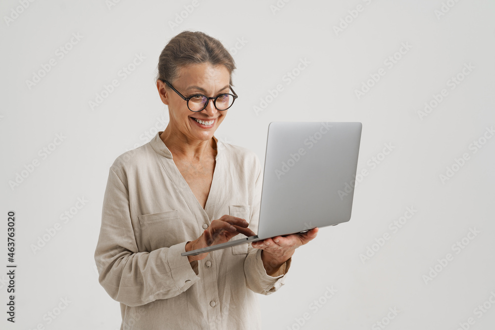 European woman in eyeglasses smiling while using laptop European woman in eyeglasses smiling while using laptop