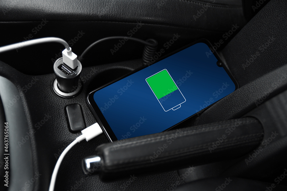 Mobile phone ,smartphone, cellphone is charged ,charge battery with usb charger in the inside of car. modern black car interior Mobile phone ,smartphone, cellphone is charged ,charge battery with usb charger in the inside of car. modern black car interior