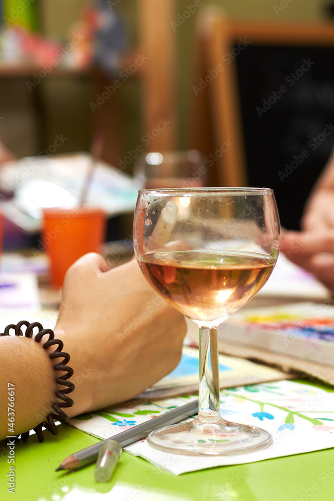 Glass of wine and female hands of the artist with brushes