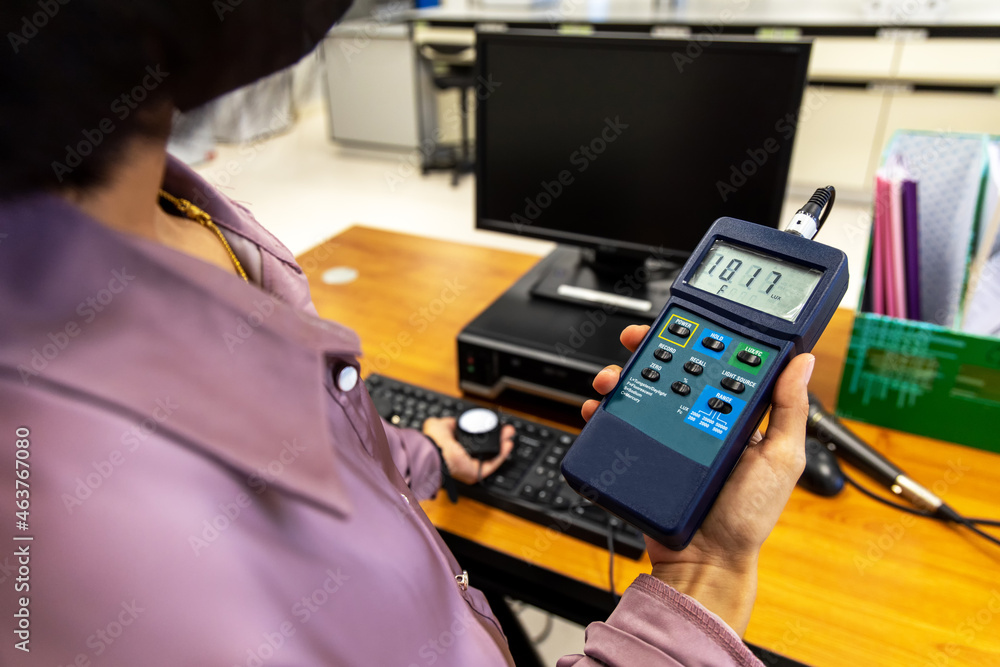 Hand holding Digital handheld light lux meter intensity of light with