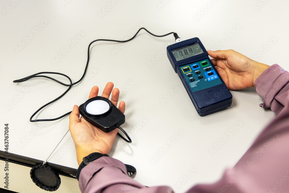 Hand holding Digital handheld light lux meter intensity of light with