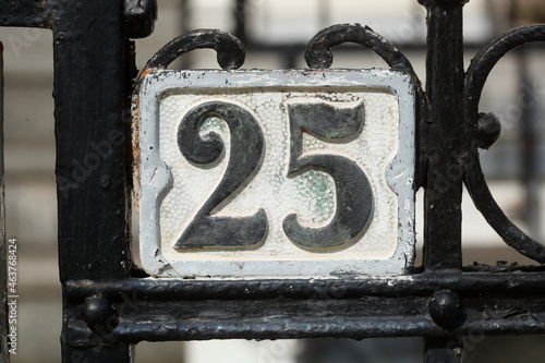Altes verwittertes Hausnummernschild Nummer Fünfundzwanzig und verzierter Metallgartenzaun, Deutschland, Europa photo