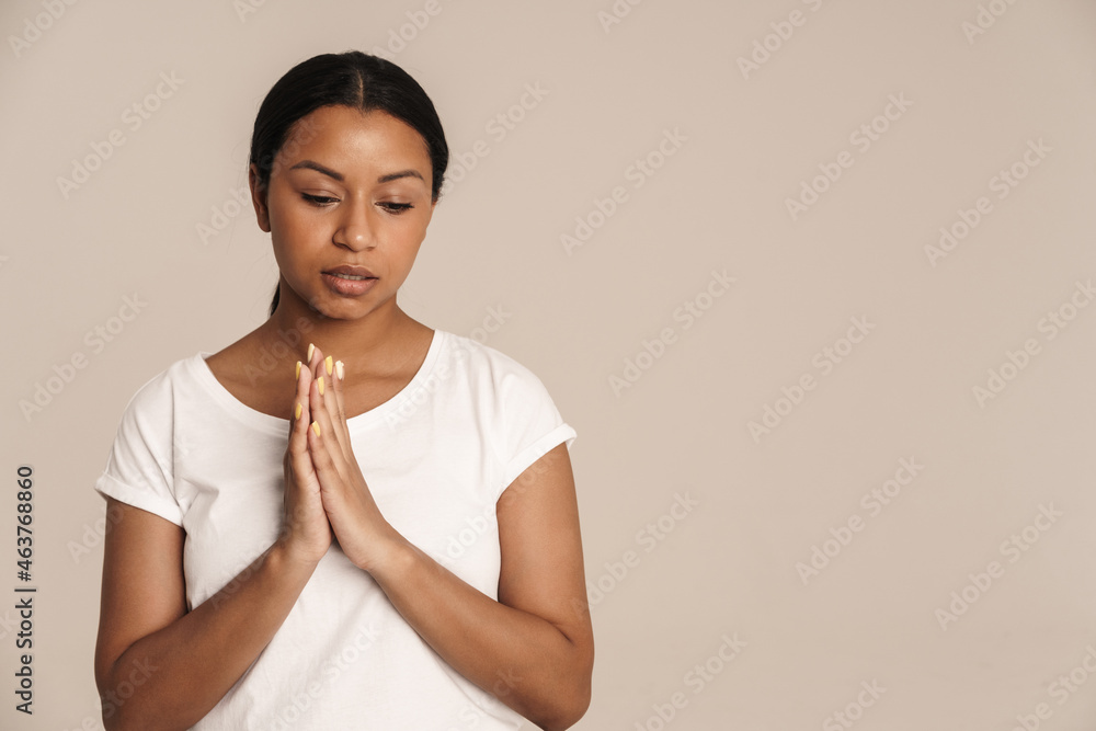 Obraz premium Young black woman wearing t-shirt posing while making praying gesture
