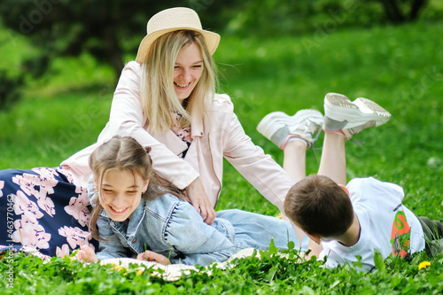 family spends the weekend in nature. happy family outdoors on the grass in a park. Mother Carrying Son And Daughter As They Play In Park. soft focus