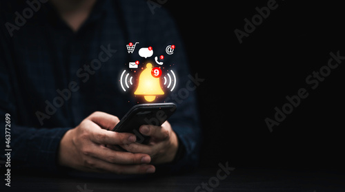 Businessman using smartphone with virtual yellow bell ringing for application notification alert concept. photo