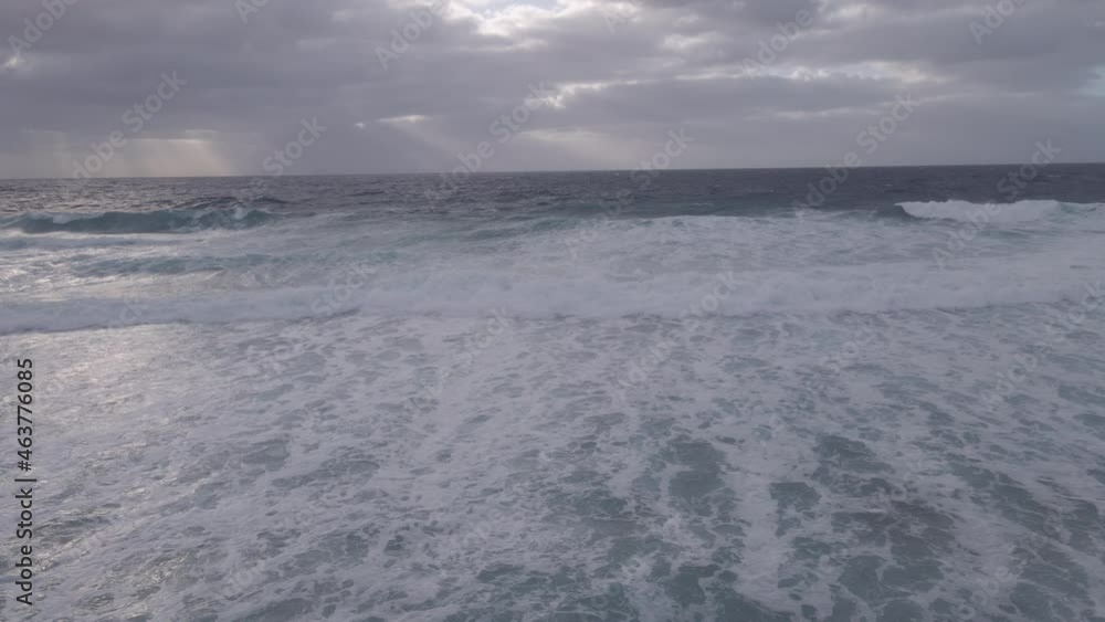 Drone flying towards ocean with waves rolling in Drone flying towards ocean with waves rolling in