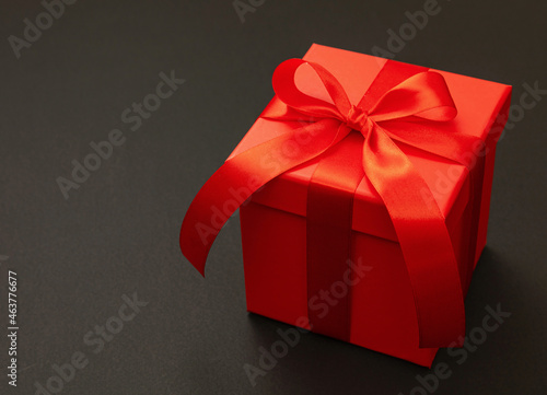Gift box red with ribbon against black background. Black Friday sale concept,
