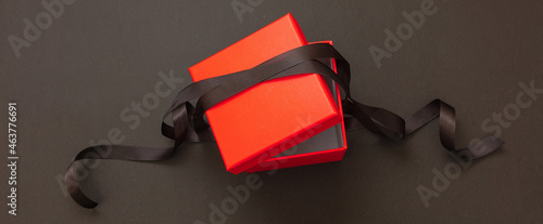 Gift box red with ribbon against black background. Black Friday sale concept,
