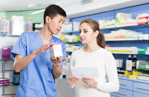 Adult woman client is asking korean man pharmacist about medicines in apothecary