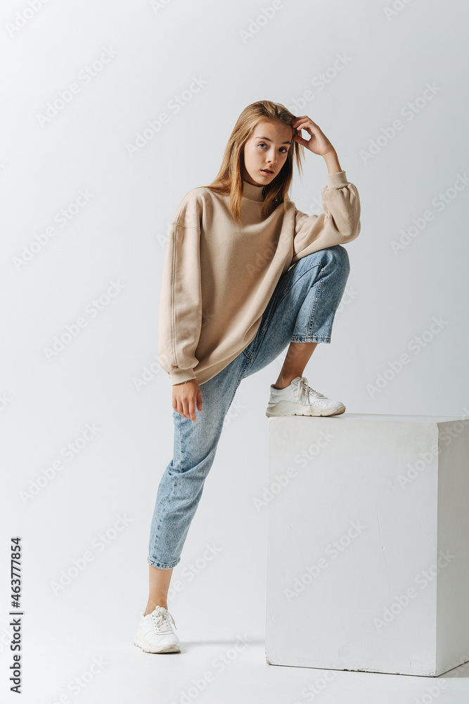 Teenage girl posing for photo, stanind on a white cube with one leg. Teenage girl posing for photo, stanind on a white cube with one leg.