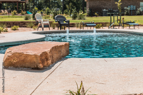 Refreshing swimming pool with a stone diving board in a luxurious backyard on a sunny summer day