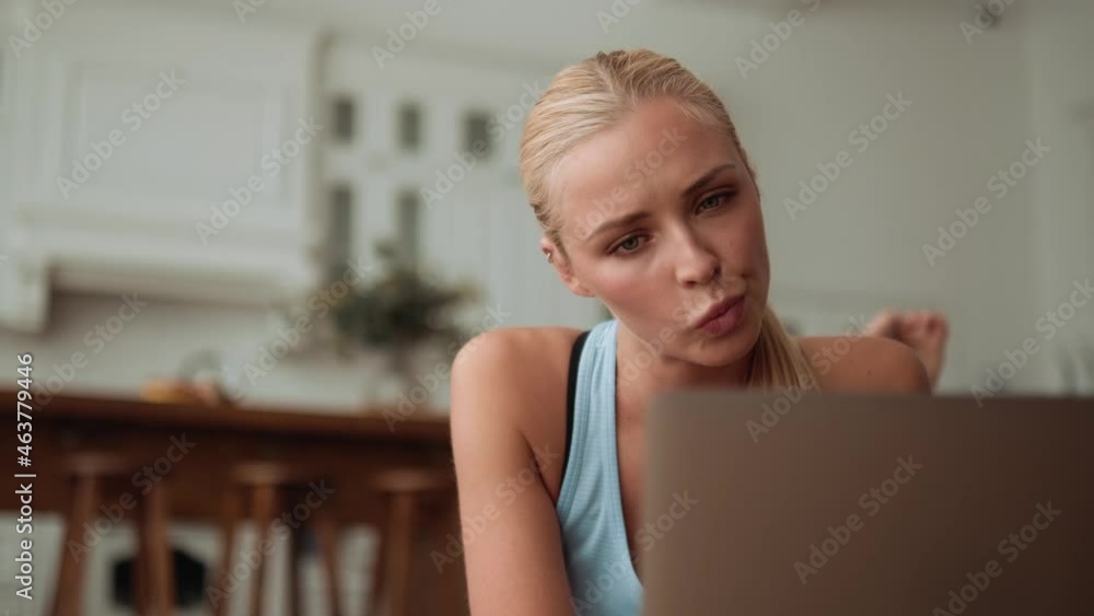 Concentrated woman looking at laptop lying on the yoga mat Concentrated woman looking at laptop lying on the yoga mat
