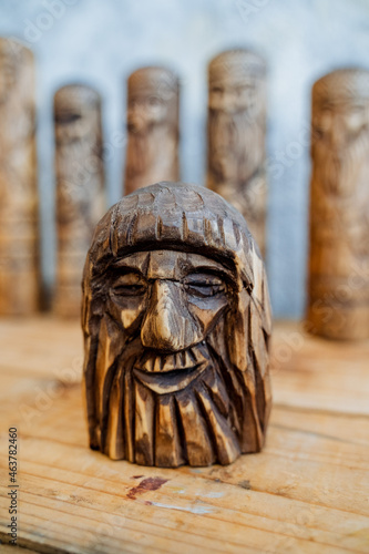 A human figure made of wood. The old man's face is carved into a wooden bar. Creativity and wood carving. Blur