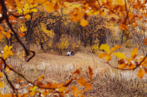 Volgograd\ Russia - october 2021: A photo of an adult and a teenager relaxing in the autumn forest in the background in a frame of yellow autumn leaves. A walk in the autumn forest