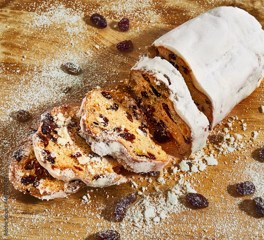 Fototapeta premium A Christmas stollen lies on a board sprinkled with powder and raisins. 