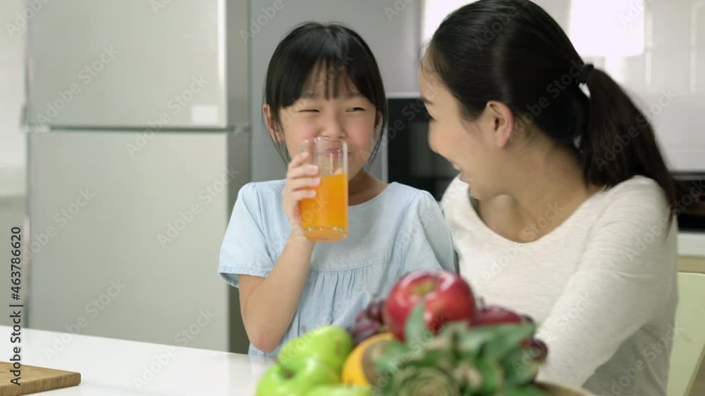 Asian family drink orange juice in kitchen room at home. Pregnant woman and daughter making orange juice smoothie at home. Family making healthy drinks while being quarantine at home. Asian family drink orange juice in kitchen room at home. Pregnant woman and daughter making orange juice smoothie at home. Family making healthy drinks while being quarantine at home.