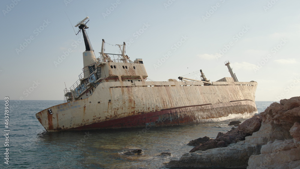 Abandoned old boat covered with rust ran aground on seaside. Neglected ship on water. Transportation concept.