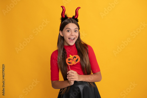 Obraz na plátně glad teen girl wearing imp horns holding pumpkin party accessory, happy halloween