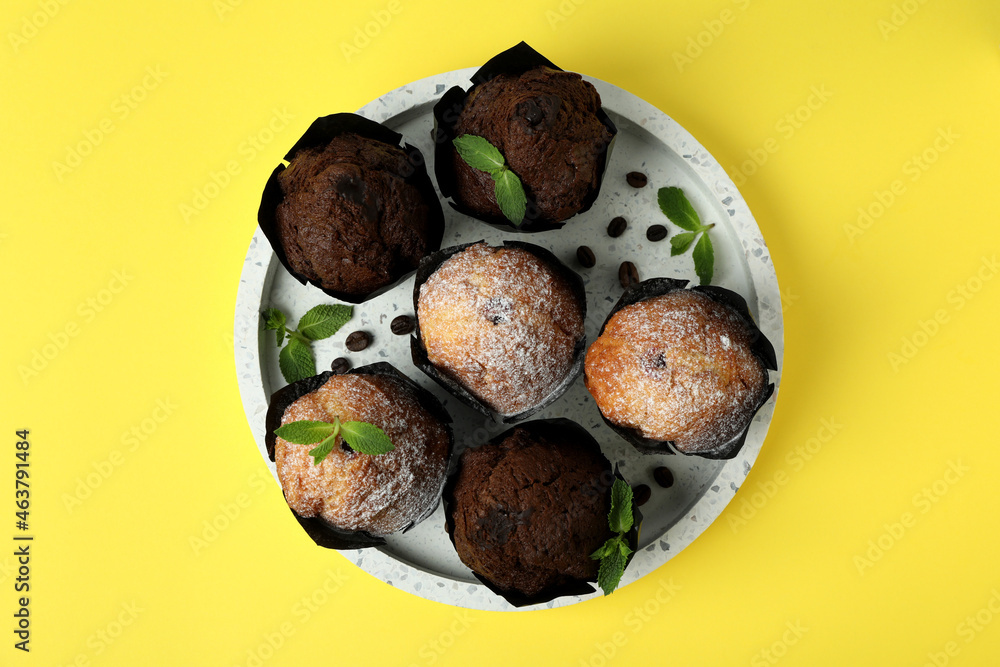 Tray with chocolate muffins on yellow background Tray with chocolate muffins on yellow background